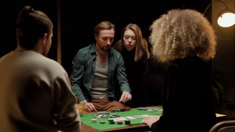 rear view of group of friends playing poker sitting on chairs at a table at home