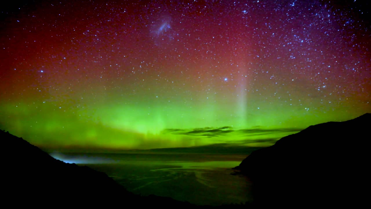 Night timelapse shot capturing auroral activity, beautiful Southern light Aurora illuminate the dark sky, exhibiting vibrant dancing waves of lights at Nugget Point New Zealand during winter
