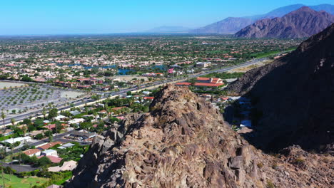 United-states-of-America-Flag-flying-in-the-wind-on-a-rocky-mountain-above-red-roofed-houses-in-a