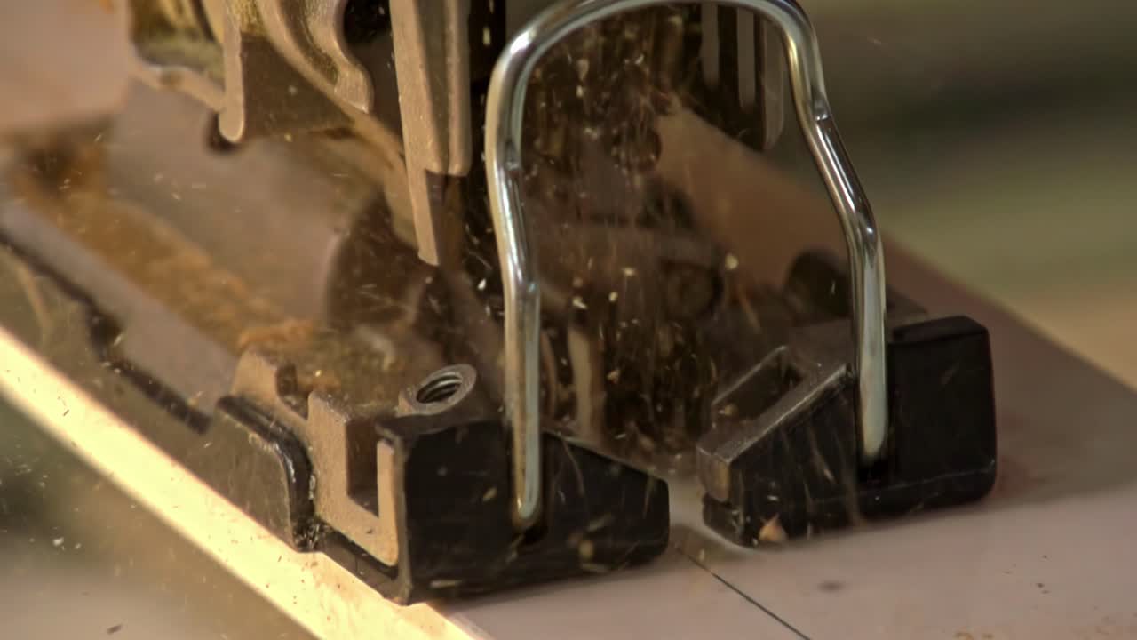 Saw blade cuts through wood in slow motion as dust particles scatter in workshop light