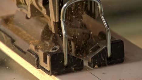 saw blade cuts through wood in slow motion as dust particles scatter in workshop light