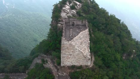antigua torre vigía cuadrada deteriorada de la gran muralla china en la cima de la cumbre de la montaña en un día nublado