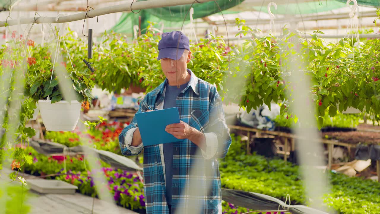 온실 2에서 식물을 감독하면서 클립보드에 쓰는 정원사