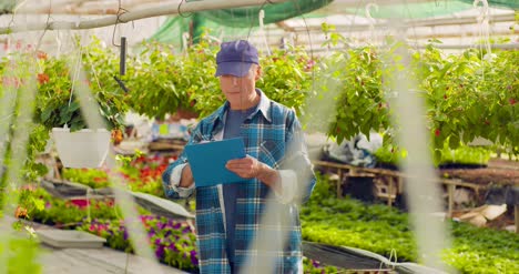 Gardener-Writing-In-Clipboard-While-Supervising-Plants-In-Greenhouse-2