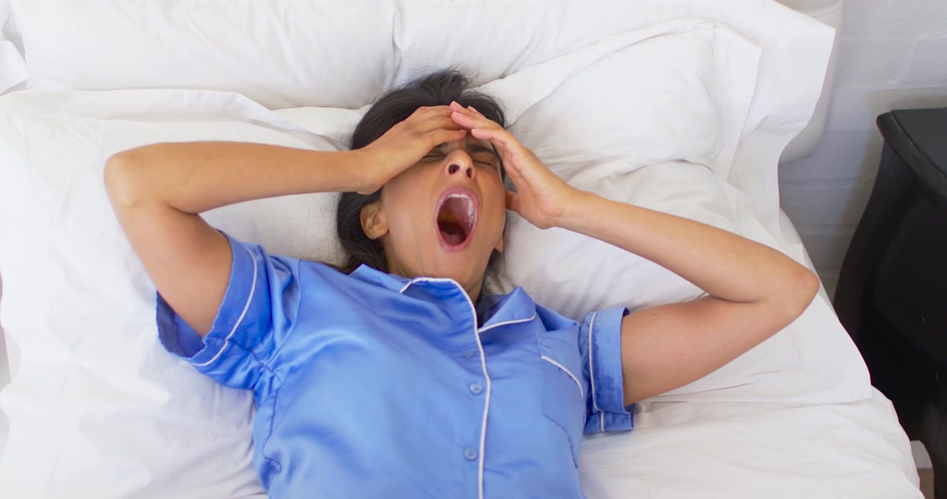 Donna sdraiata a letto che si sveglia alla luce, con un grafico del sonno animato che sincronizza sbadigli e stiramenti per la salute