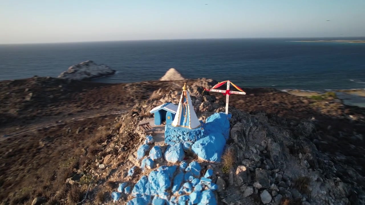 Ripresa cinematografica con drone orbitale del santuario della Virgen del Valle e della Cruz de Mayo che si affaccia sul Mar dei Caraibi al tramonto a Los Roques, Venezuela
