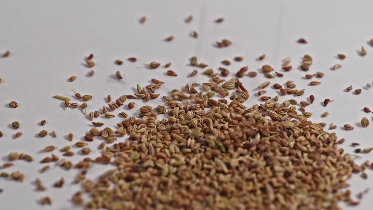 carom seeds or Ajwain falling on white surface and bouncing, 4k, stable shot