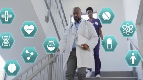 animation of medical icons over african american female and male doctor rushing down staircase