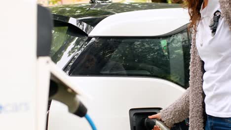 Mujer-Cargando-Coche-Eléctrico-En-La-Estación-De-Carga-4k