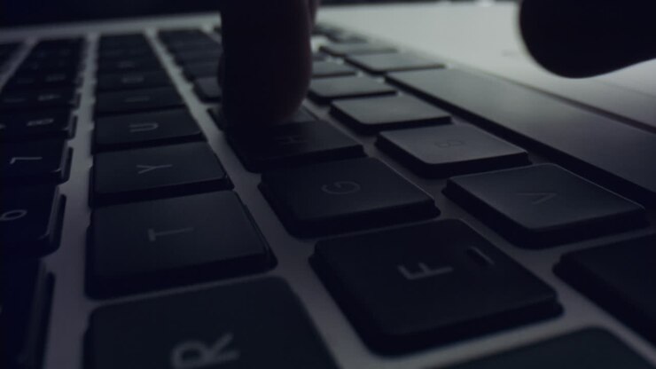 Person benutzt Laptop-Computer. Männerhände tippen auf der schwarzen Tastatur des Laptops.