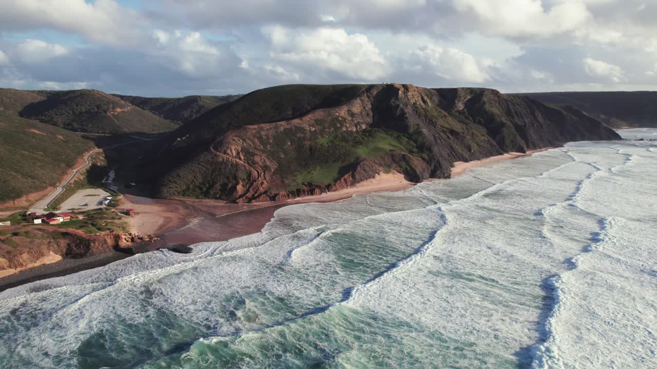 Aerial 4k drone establishing shot of continuous waves at praia da Cordoama hidden cliff coastline near the Algarve region of Portugal