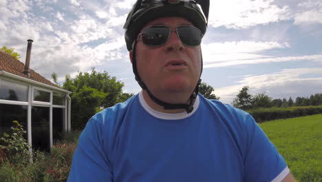 closeup view on a man cycling on bike on footpath, shows being outdoors, and seeing countryside and also houses