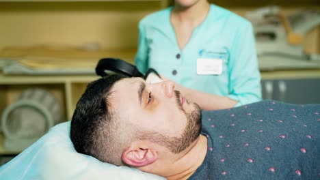 medical worker and a male patient in clinic. nurse puts on headphones to the sick patient. healthcare concept.