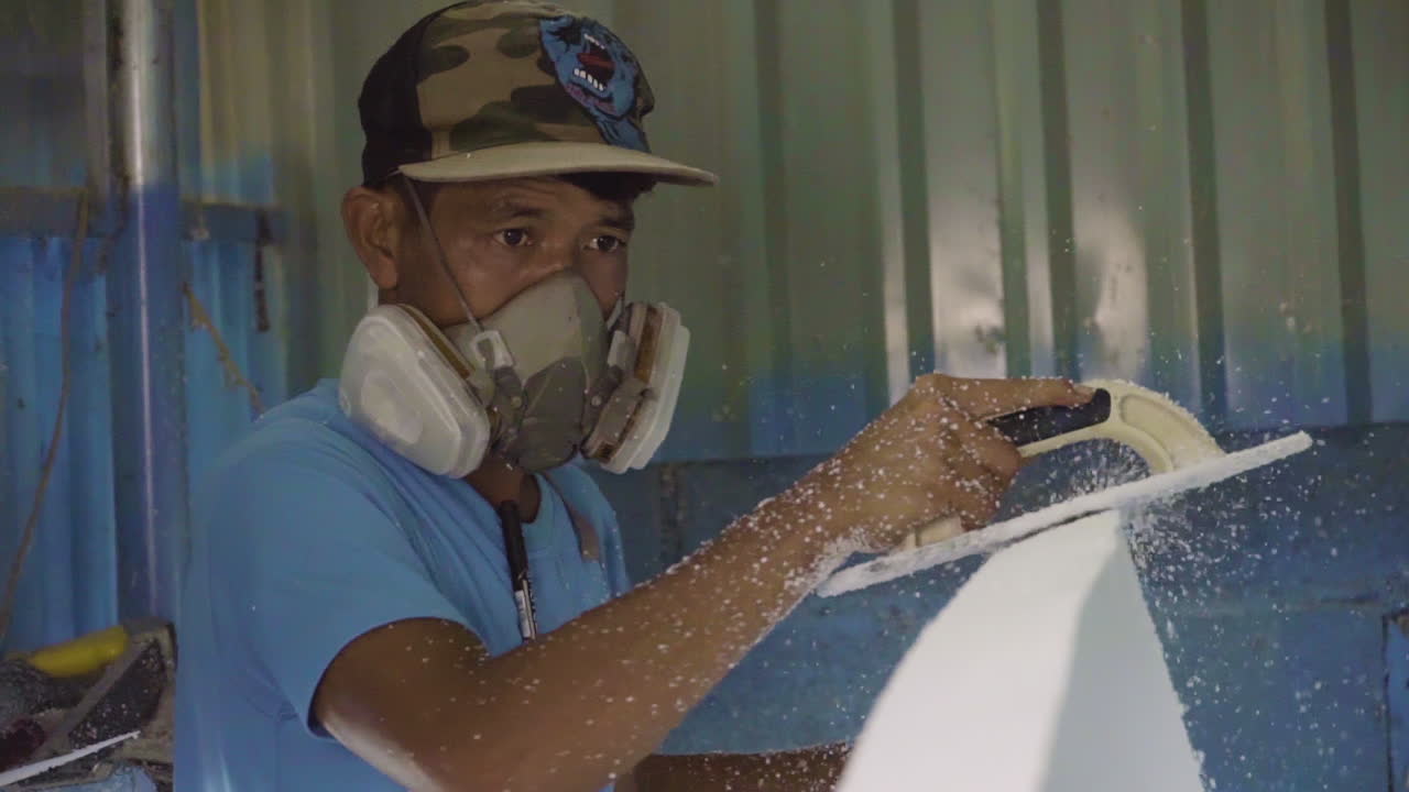 서프보드를 만드는 동안 얼굴 보호대를 착용한 장인, 핸드헬드 보기