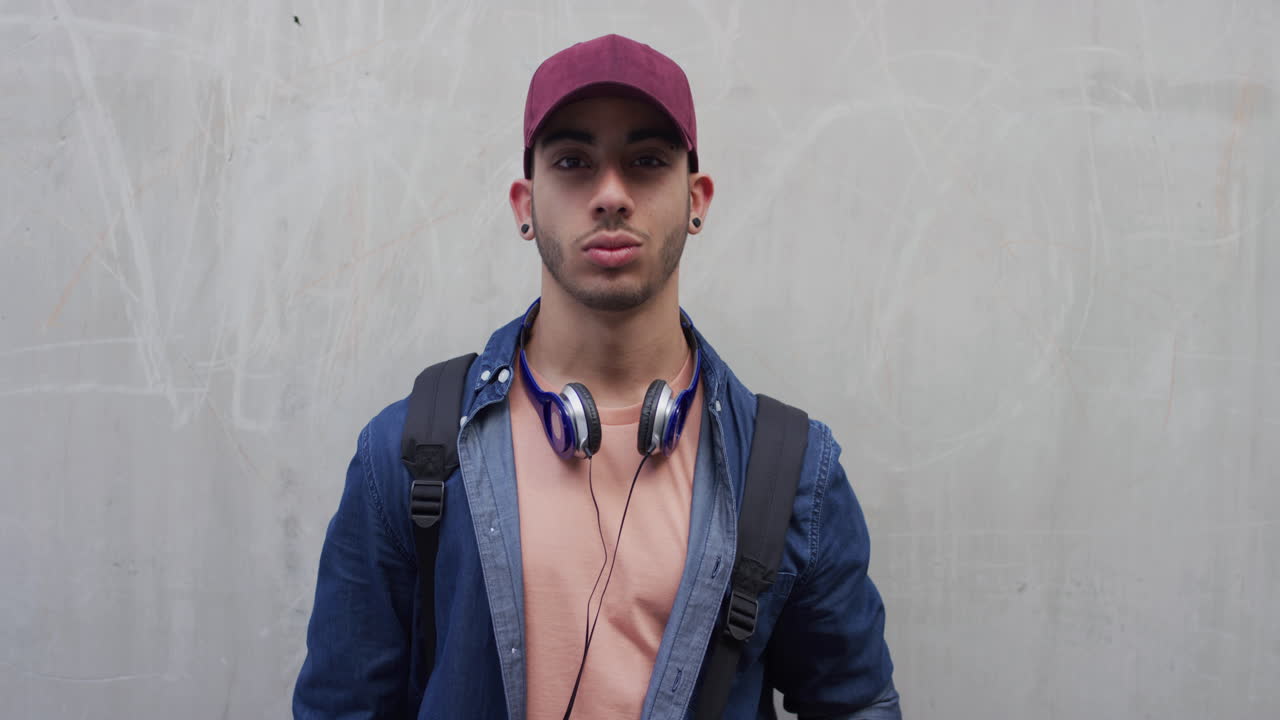 retrato de un joven confiado, estudiante, hombre hispano, vestido con moda, disfrutando del estilo de vida, juventud urbana despreocupada, cámara lenta.