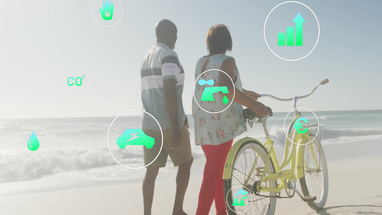 man walking alongside woman pushing bicycle on beach, showing floating environment bar graph icons