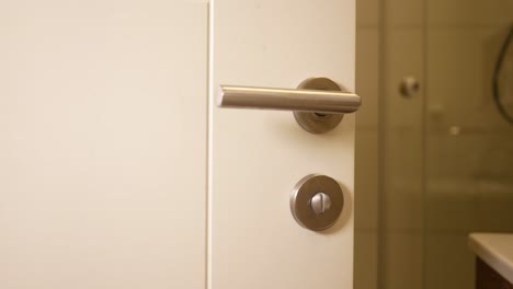 close-up of a white bathroom door with a metal handle and lock.