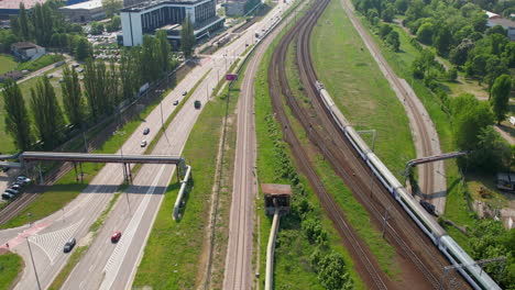 Aerial-birds-eye-flight-over-highway-with-traffic-and-train-in-Gdansk-during-sunny-day,-Poland---Establishing-aerial-shot