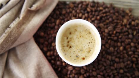 disposable cup with coffee beans on wooden plank