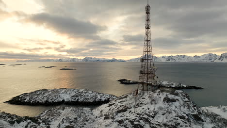 mobile communication tower against golden sunrise sky, henningsvaer