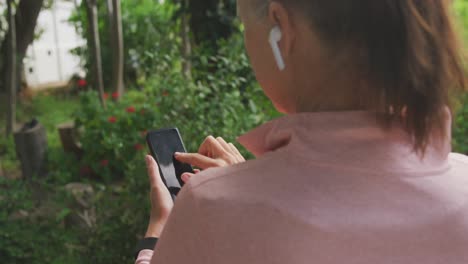 Rear-view-of-senior-woman-using-smartphone-in-the-park