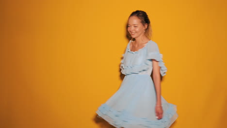 woman in a light blue dress against a yellow backdrop