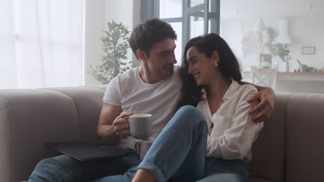 happy couple drinking coffee at home . sexy man and woman talking at sofa.