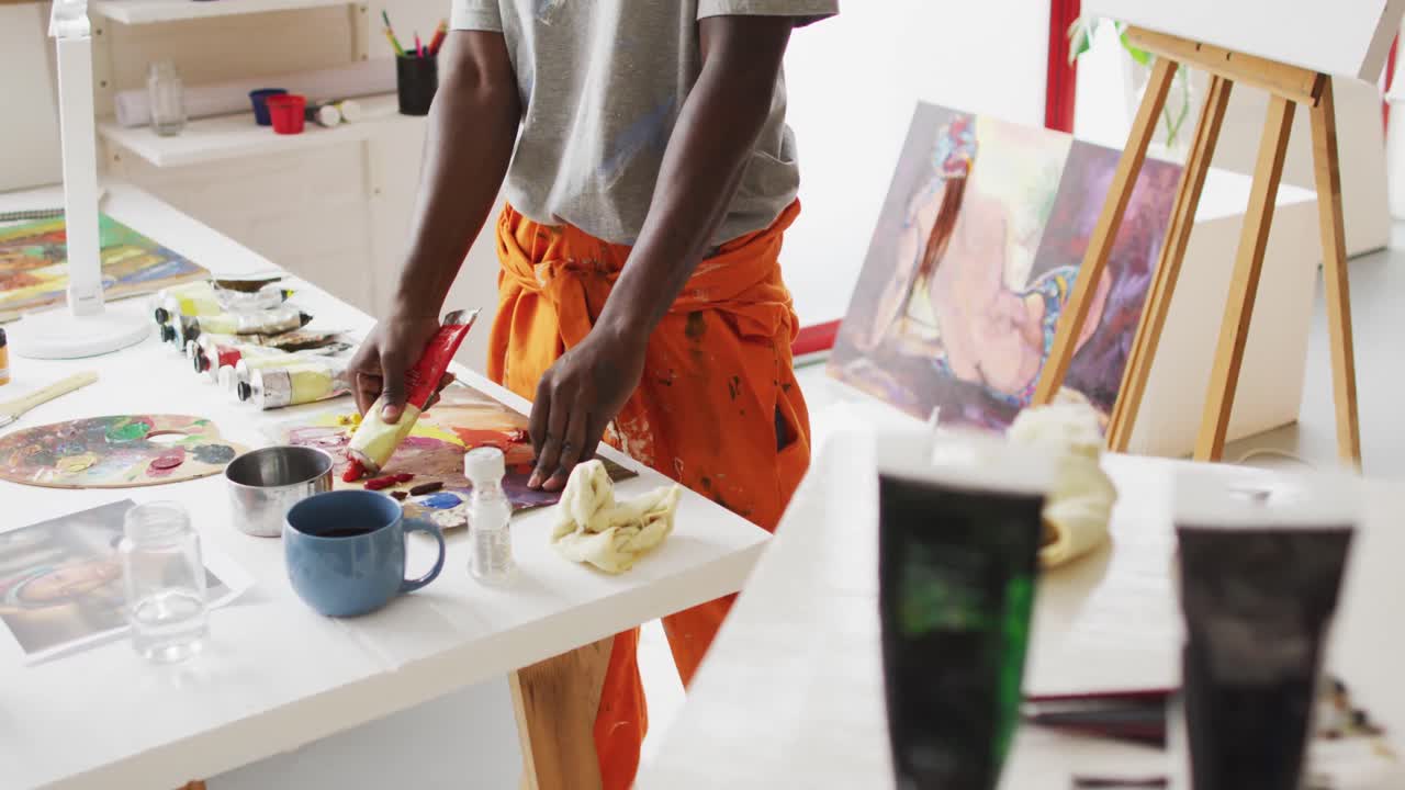 Midsection of african american male painter mixing paint in artist studio