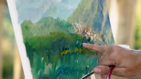 person pointing at a painting of mountains and trees