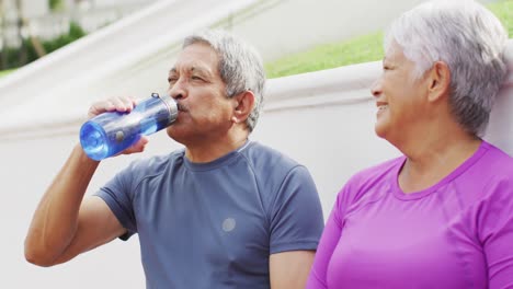 Video-De-Una-Feliz-Pareja-Birracial-De-Ancianos-Bebiendo-Agua-Después-Del-Partido-En-Las-Gradas