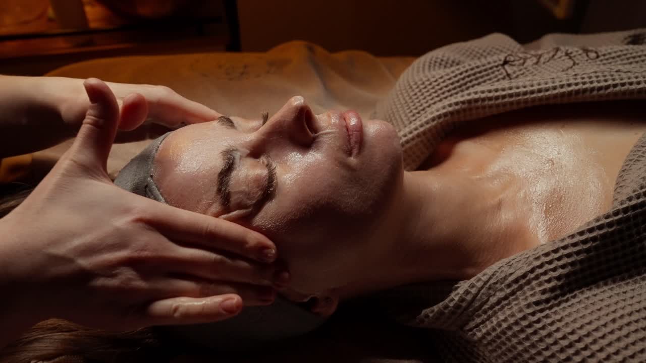 Kvinde får afslappende ansigtsmassage i en spa