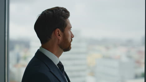 thoughtful businessman standing window watching cityscape closeup. company owner