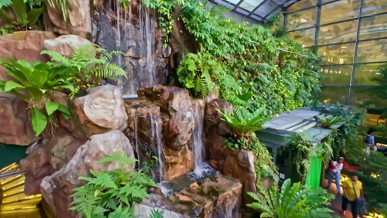 Profile view of man made waterfall in Singapore Changi Airport. Water dripping from rocks.