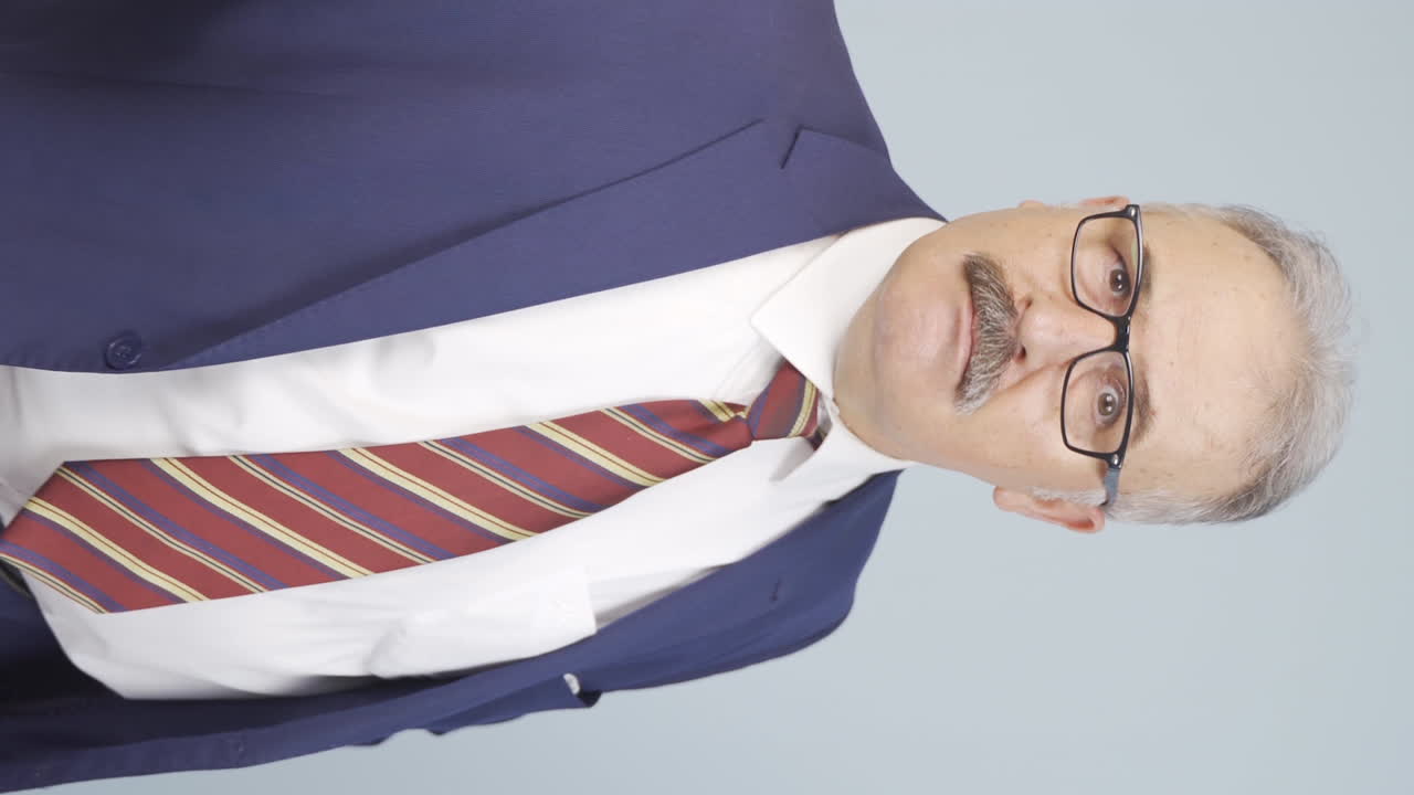 video vertical de un viejo hombre de negocios enojado mirando a la cámara.