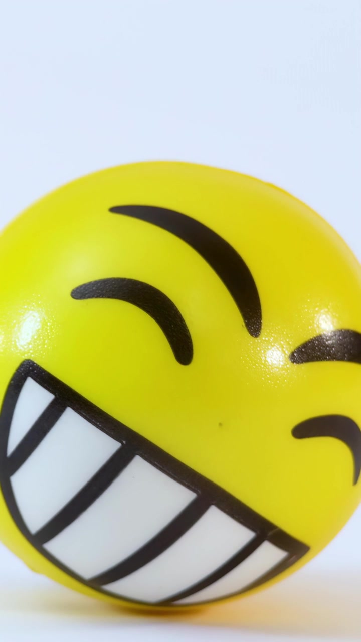 Palla antistress a forma di faccina gialla sorridente che ruota su sfondo bianco