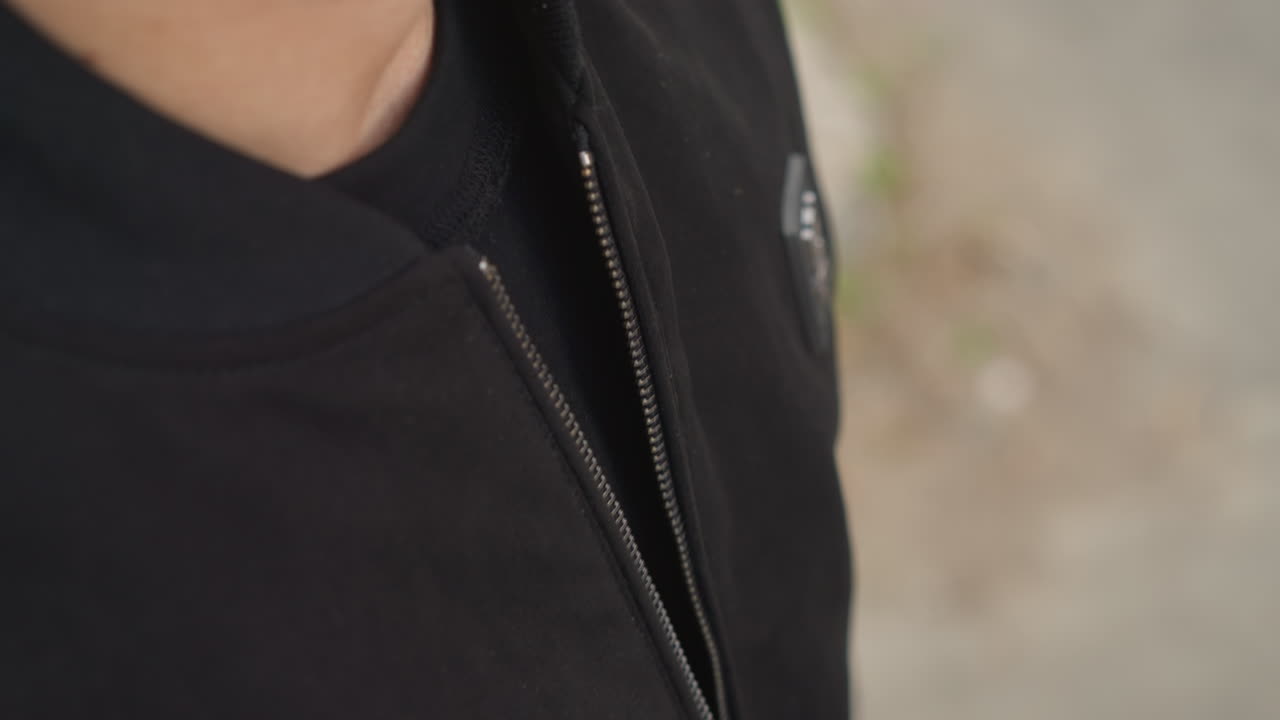 Collar de alisado individual antes de la sesión; persona que se ajusta la ropa de abrigo preparándose para la sesión de fotografía; modelo masculino que prepara la ropa de abrigo arreglándose la cremallera momentos antes de la captura de la foto