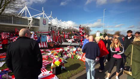 people pay their respects at the gordon banks statue by the stoke city stadium, people signing shirts, scarves, flags and the book of remembrance