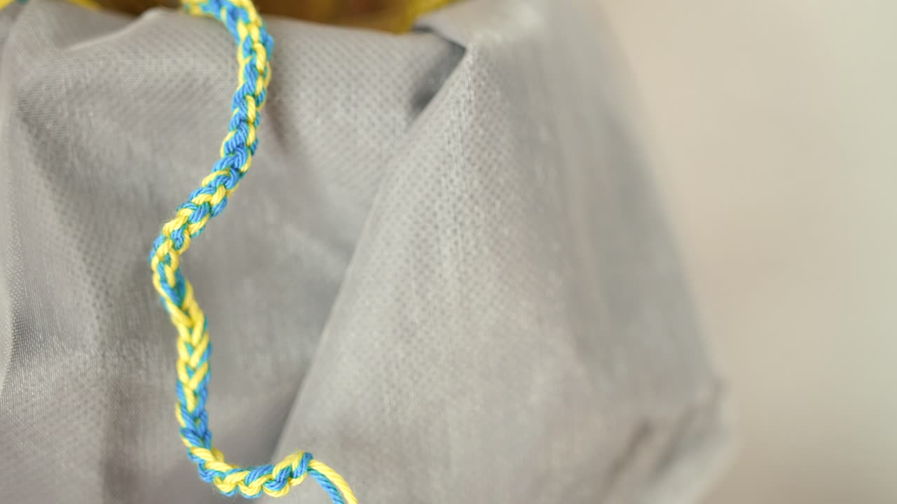 vista de cerca de una pulsera casera colgada en apoyo al pueblo ucraniano haciendo una pulsera con los colores de la bandera ucraniana como los colores amarillo y azul