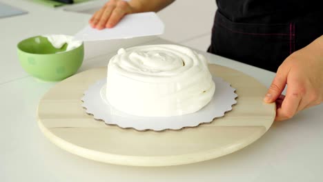 el confitero cubre el pastel con crema.