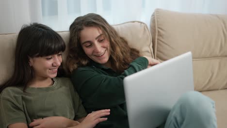 Zwei-Hübsche-Kaukasische-Mädchen-Amüsieren-Sich-Beim-Anschauen-Von-Comedy-Filmen-Auf-Dem-Laptop-Auf-Der-Couch-Im-Zimmer