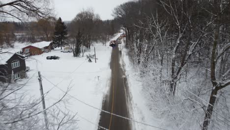 aerial flying towards a snow plough truck clearing a snowy road in rural ontario