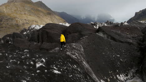 glaciar svinafellsjokull, islandia - una persona caminando a través de un glaciar - toma aérea de un dron