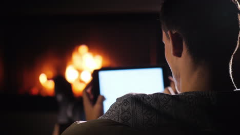 silhouette of man with tablet resting at home by the fireplace