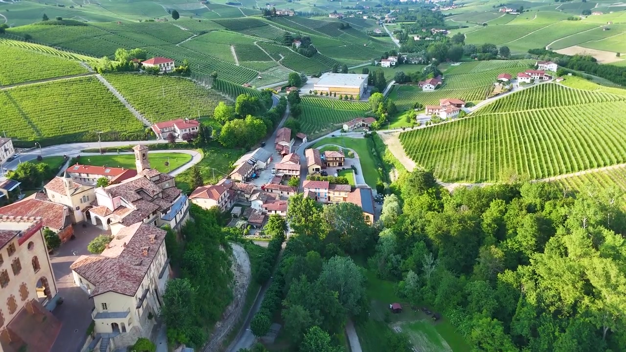 Ripresa aerea con drone che effettua una panoramica sull'architettura storica italiana e sulle lussureggianti colline ondulate di vigneti