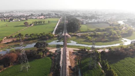 a railway bridge crossing thought the green fields and over the small canal