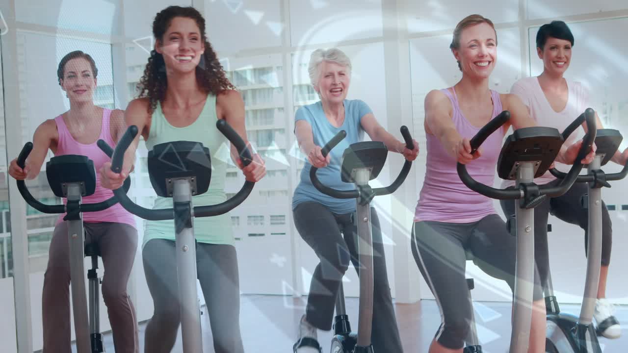 Five women starting pedaling at cue, smiling on bikes with overlays sweeping over them for fitness