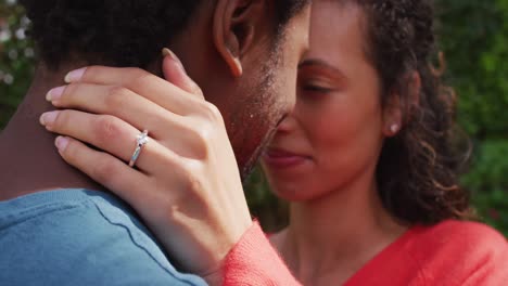 Close-up-of-happy-biracial-woman-with-engagement-ring-on-hand-hugging-to-fiance