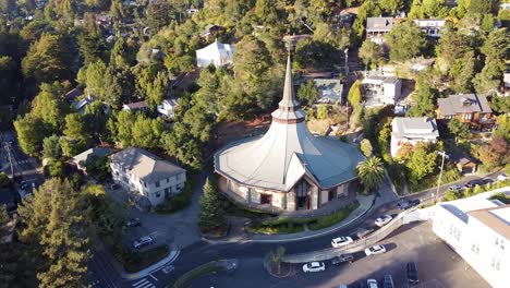 vista aérea de una iglesia moderna en el medio de la ciudad con muchos árboles y vegetación al sol naciente