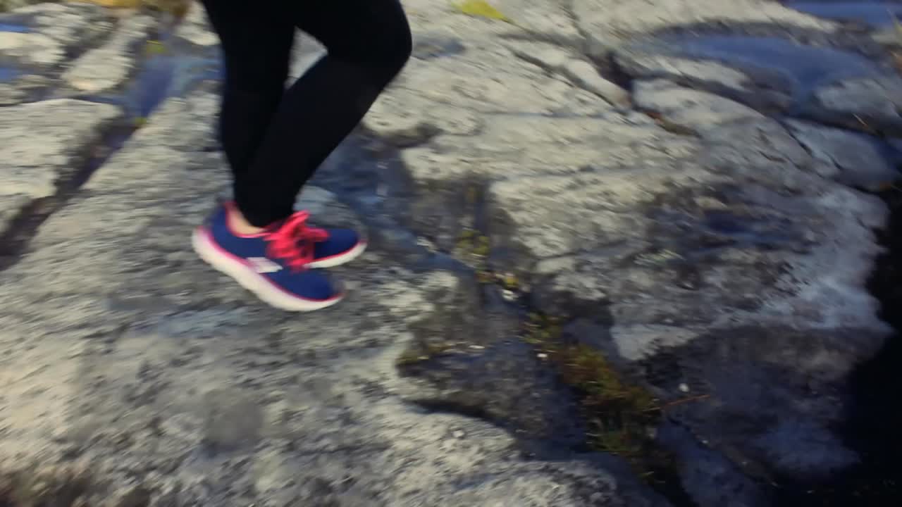 camera following the step of a woman, walking on a trail in table mountain