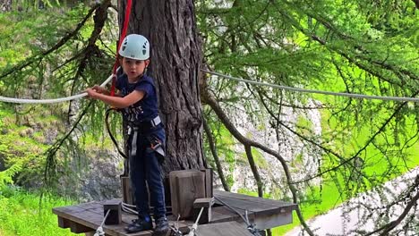 slow motion frontal view of a young boy on a via ferrata adventure in the dolomites, italy, a fun and challenging outdoor activity